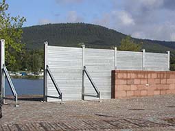 Foto der festen Schutzmauer mit teilweise aufgebautem kombinierten System auf der Mauer und in einem Durchlass