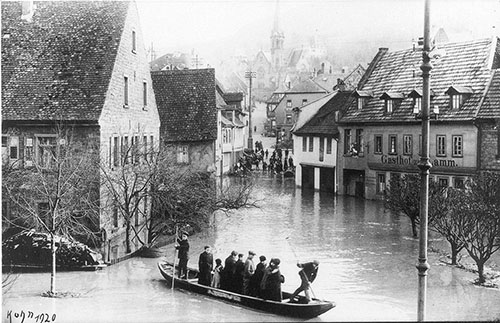 Menschen werden in einem Kahn durch die überschwemmte Stadt gefahren